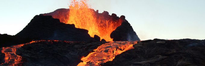 top of volcano, with river of orange lava flowing down it