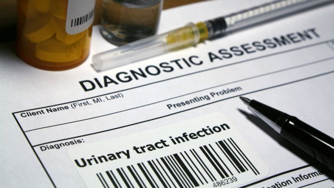 Paper that reads "Diagnostic assessment" and "Diagnosis: Urinary Tract Infection" appears next to a syringe and a pill canister.