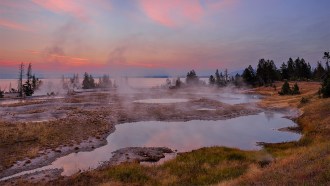 A photograph of the landscape in West Thumb Geyser Basin and Yellowstone Lake (in the photo's background)