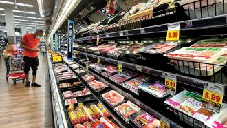 a customer surveys the meat section in a grocery store