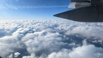 A photograph of a plane flying over Arctic clouds.