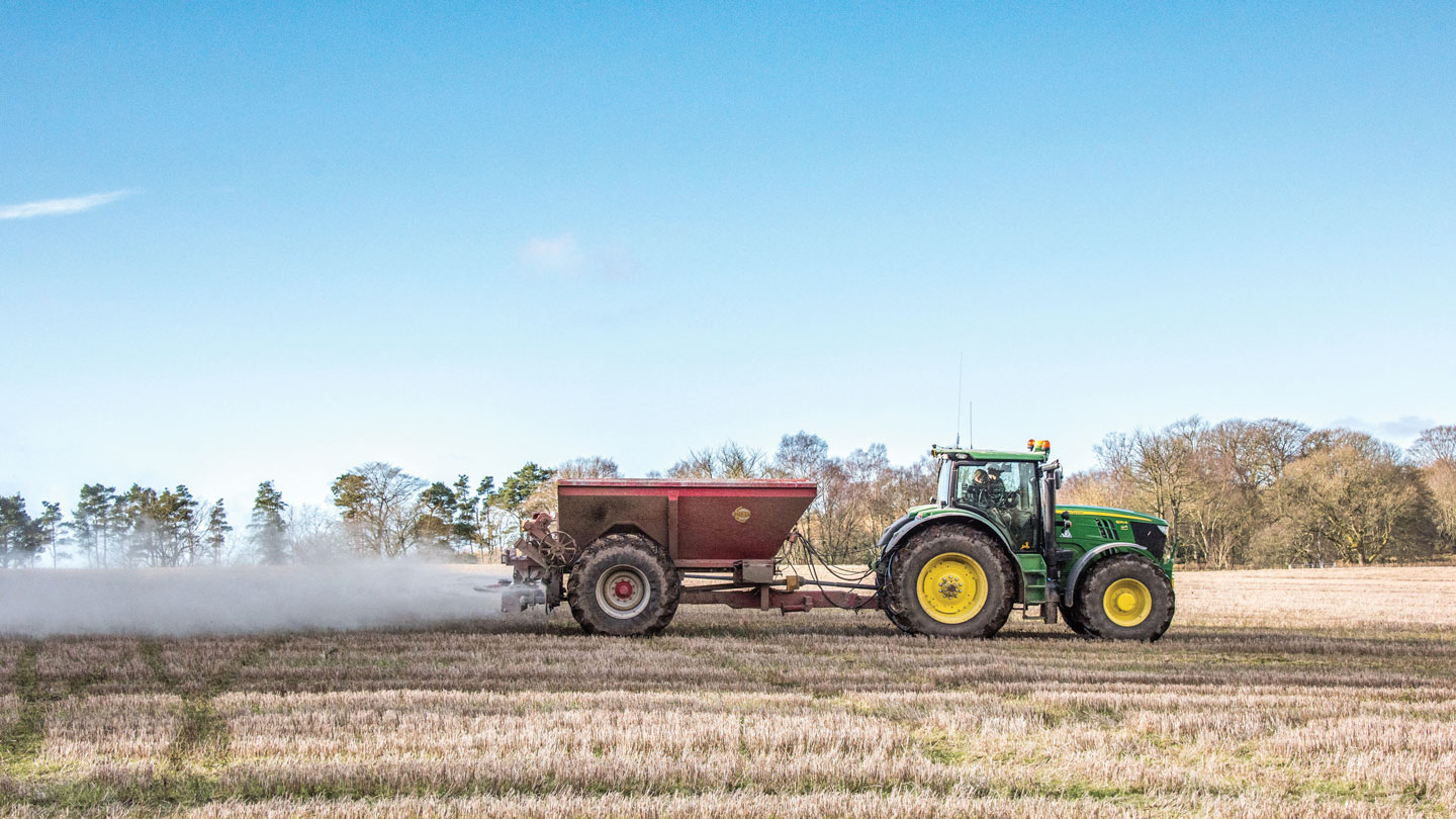 A tractor spreading rock dust in a field