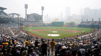 photo of a baseball stadium with a cityscape obscured by smoke in the background