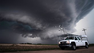 A truck is parked in the foreground, with a large storm system in the background.