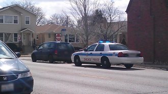 A photo of a Chicago police car parked behind a dark-colored van.