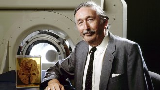 a man in a suit stands in front of a CT scanner