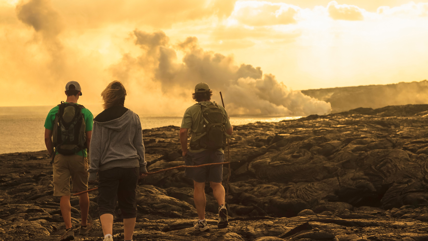 three people walking near solidified lava flow