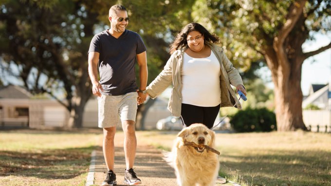 A couple walking outside with a dog