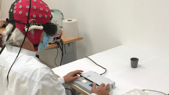 A side view of a man wearing an EEG cap and dark goggles